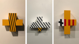 3 wooden sculptures of crosses with varying colours geometric designs